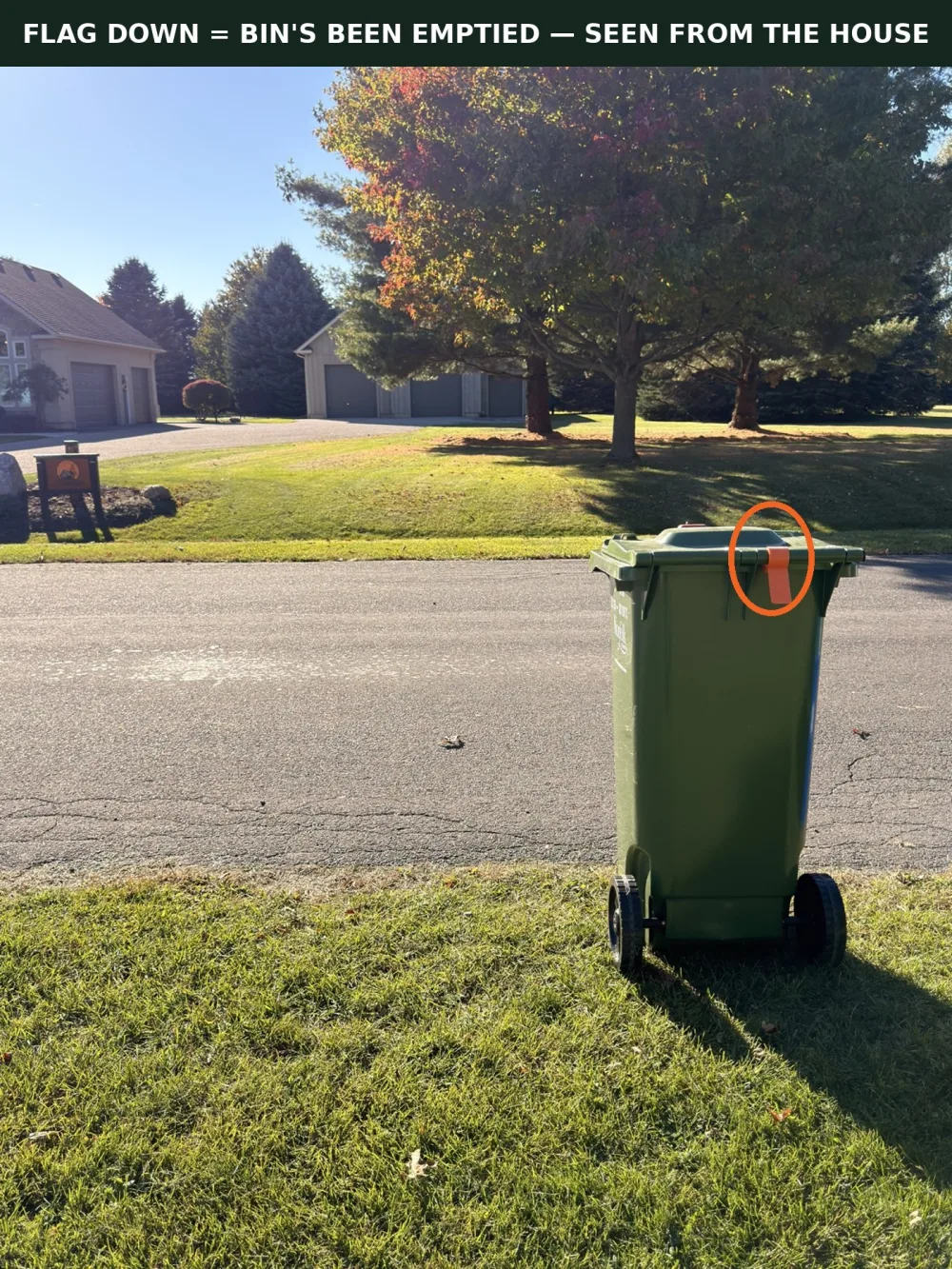 The orange BinGone flag visible on a green cart at the curb, seen from the house